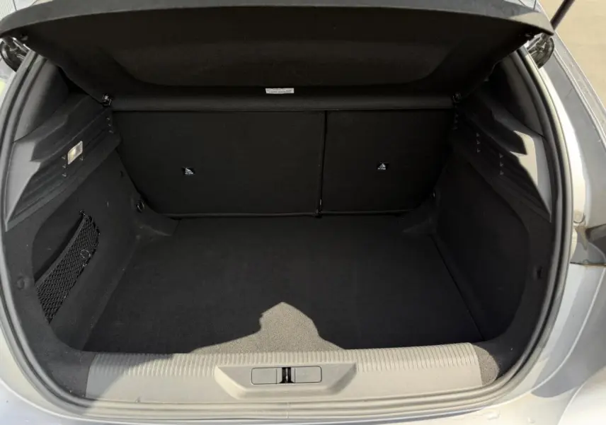 Vue intérieure du coffre ouvert d'une Peugeot 308 gris Artense, montrant l'espace de rangement vide et les finitions en tissu noir.
