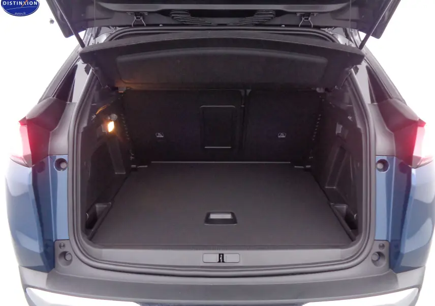 Coffre ouvert d'un Peugeot 3008 2023 bleu Célèbes Métal, vue arrière montrant un espace de chargement spacieux et éclairé.
