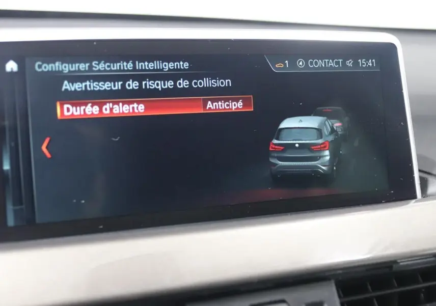 Écran de bord BMW X1 affichant l'alerte de risque de collision avec illustration du SUV gris vu de l'arrière.