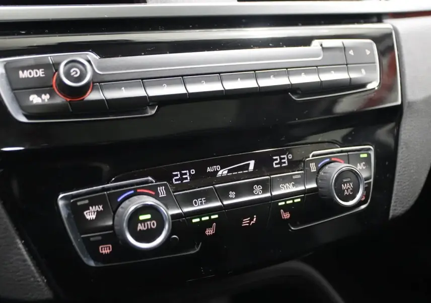 Gros plan sur la console centrale noire du BMW X1 2019, mettant en valeur les commandes de climatisation digitale.