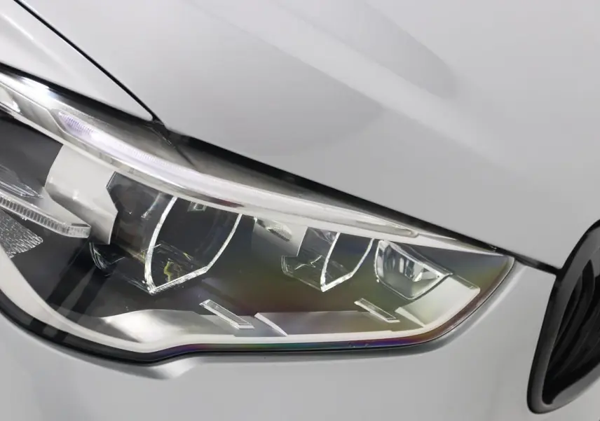 Gros plan sur le phare avant droit d’un BMW X1 sDrive 18D argent métallisé avec détails LED et calandre noire partielle visible.