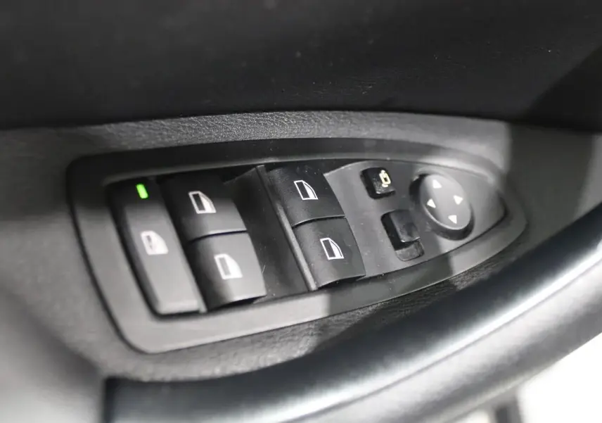 Commande des vitres électriques et réglage des rétroviseurs sur la porte côté conducteur d'une BMW X1 argentée 2019.