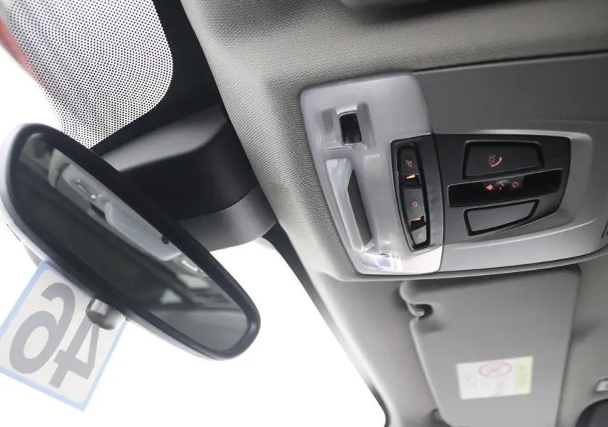 Vue intérieure du plafond avec rétroviseur et commandes d'éclairage du toit ouvrant d'une BMW X1 argentée 2019.