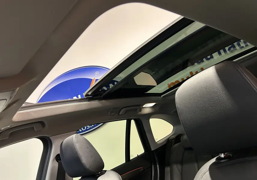 Vue intérieure du BMW X1 sDrive 18D 2019 argent métallisé, mettant en valeur le toit ouvrant panoramique et les sièges en cuir noir.