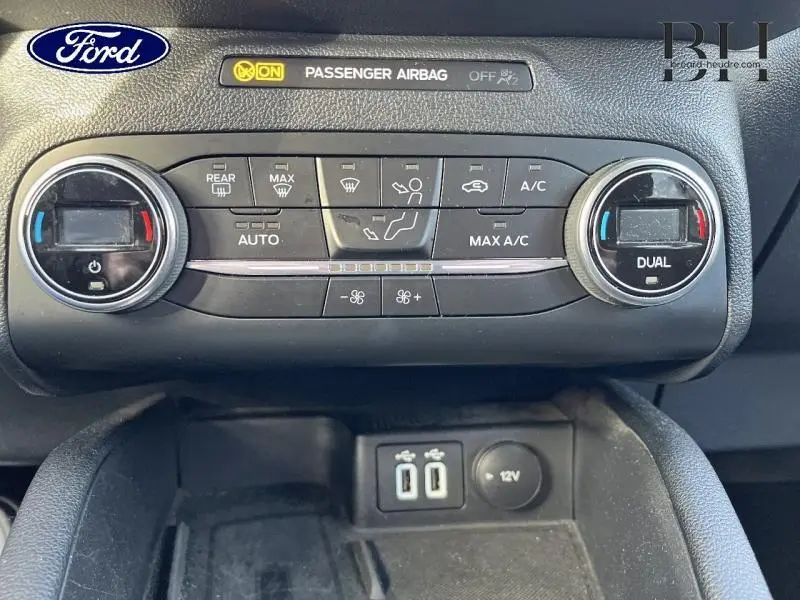 Vue rapprochée de la console centrale du Ford Kuga 2020, avec commandes climatisation bi-zone et ports USB visibles.