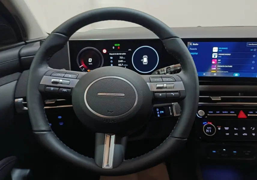 Vue intérieure centrée sur le volant cuir et les écrans digitaux du tableau de bord du Hyundai Tucson 2025.