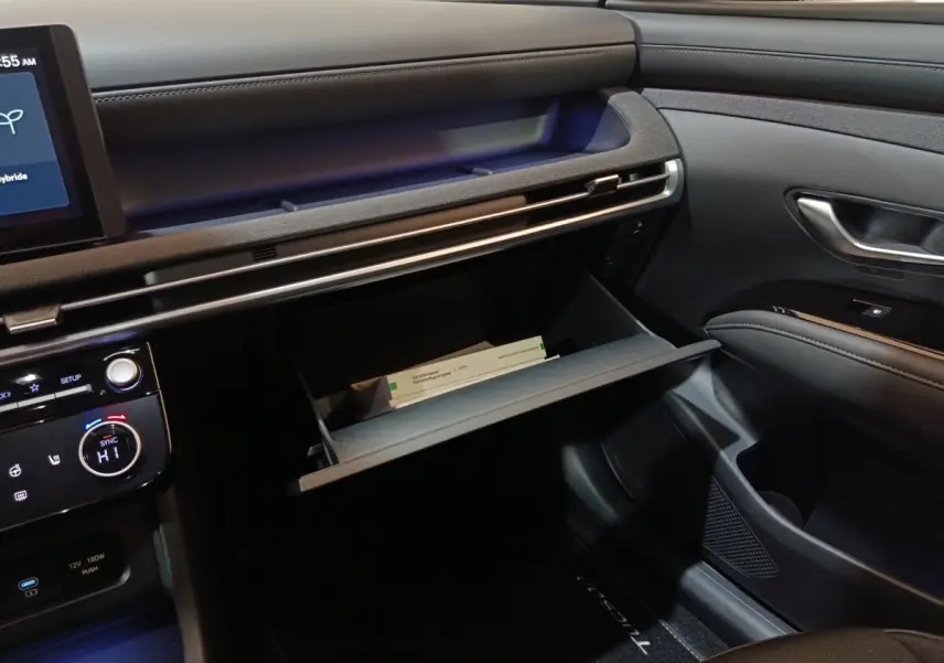 Intérieur du Hyundai Tucson 2025 gris clair, vue côté passager avec boîte à gants ouverte et tableau de bord moderne.