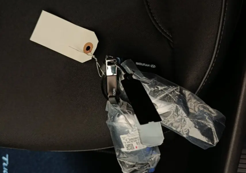 Clé de voiture Hyundai Tucson 1.6 Hybrid posée sur un siège tissu gris foncé à l'intérieur du véhicule.