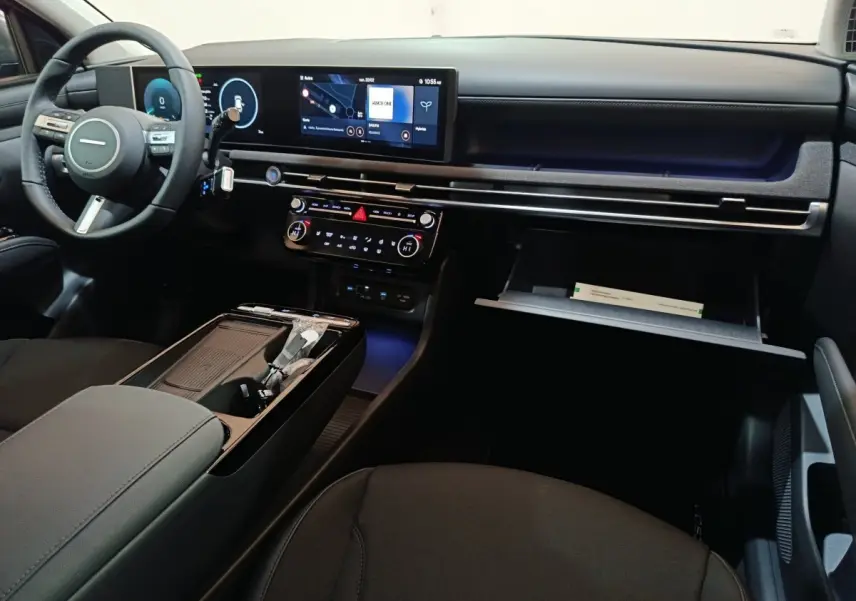 Intérieur avant du Hyundai Tucson 1.6 Hybrid 2025, tableau de bord moderne avec écran tactile 12,3 pouces et volant cuir noir.