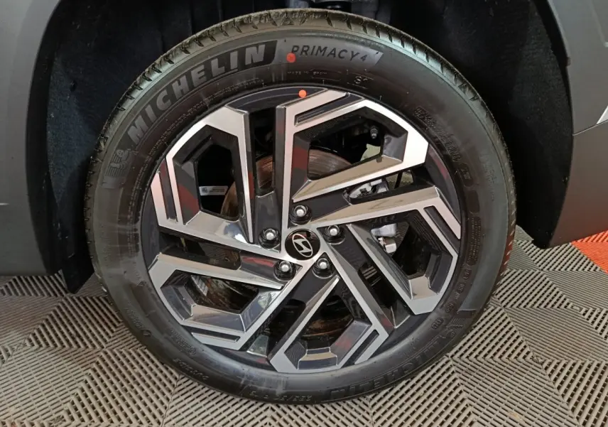 Gros plan sur la roue avant droite du Hyundai Tucson gris clair 2025 avec jante alliage au design géométrique.
