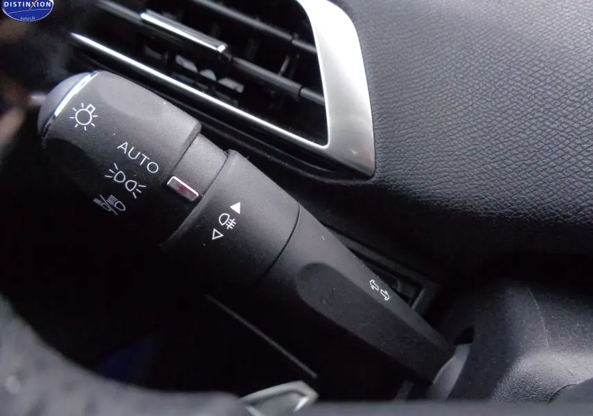 Gros plan sur la commande des feux et clignotants à gauche du volant dans l'habitacle noir du Peugeot 3008 2023.