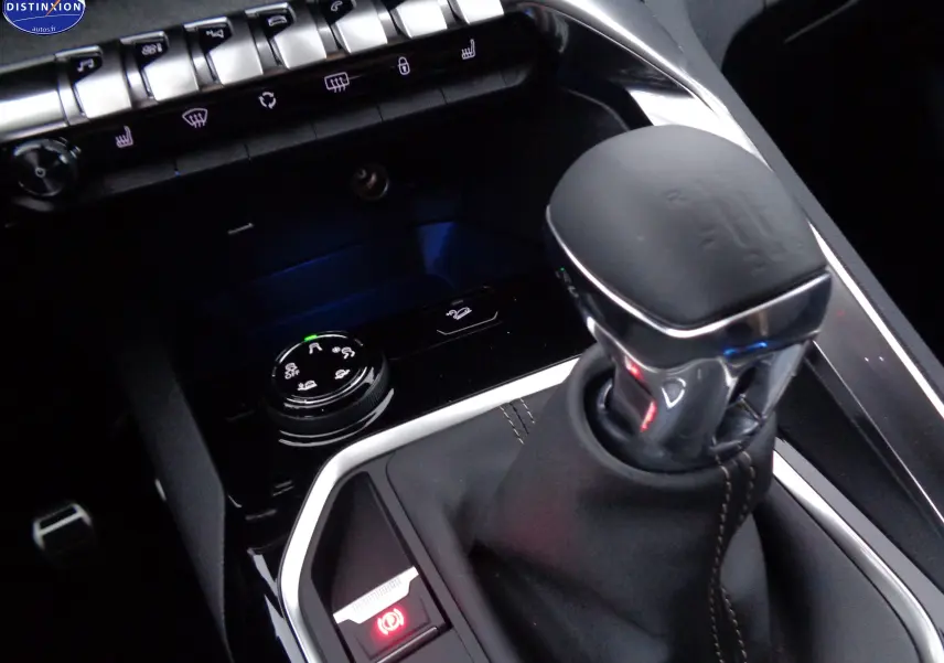 Gros plan sur le levier de vitesse manuel noir et les commandes centrales du Peugeot 3008 GT 2023 en intérieur sombre.
