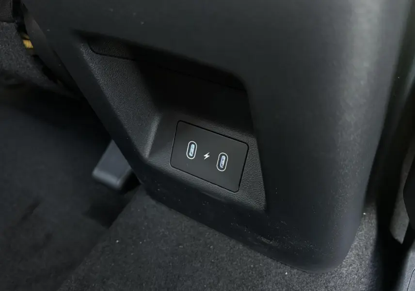 Prise USB double en gros plan sur la console arrière noire du Hyundai Tucson Cypress Green 2025.