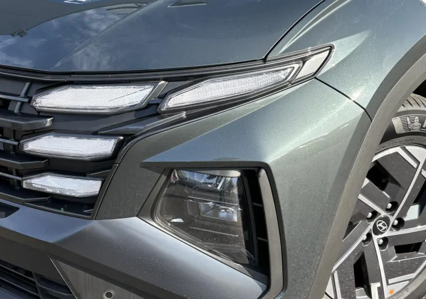 Gros plan sur l'avant droit du Hyundai Tucson Cypress Green 2025, mettant en valeur ses phares LED et jantes alliage.