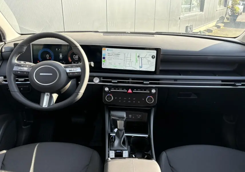 Vue intérieure avant du Hyundai Tucson 2025 avec tableau de bord numérique et écran tactile large, finition noire élégante.