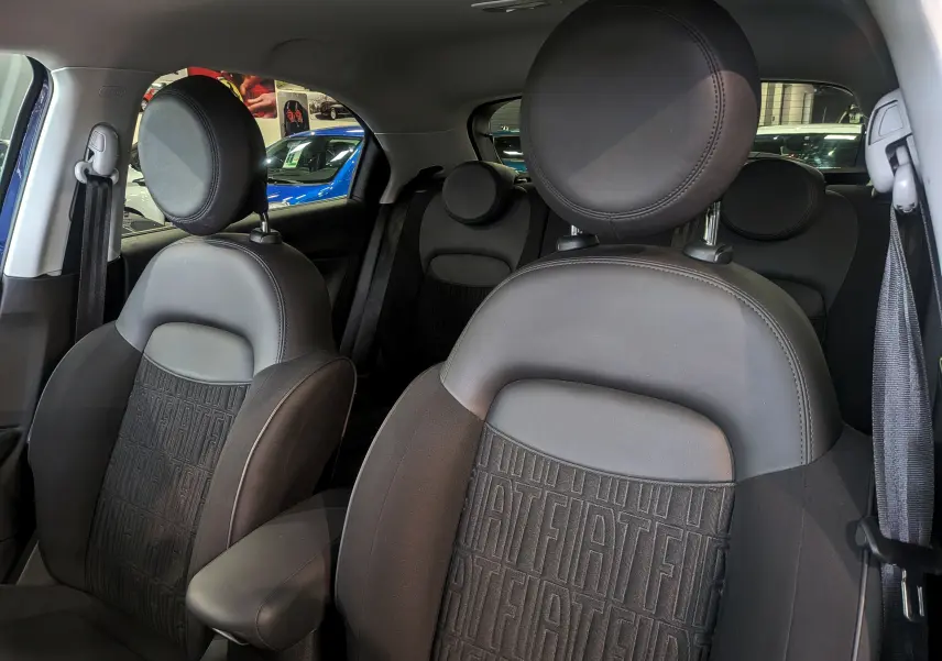 Vue intérieure des sièges avant en cuir noir avec logo FIAT embossé sur les dossiers du FIAT 500X 2024.