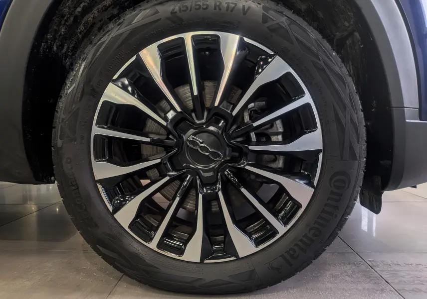 Gros plan sur la jante alliage noire et argentée du FIAT 500X Bleu Venezia, mettant en valeur le logo central distinctif.