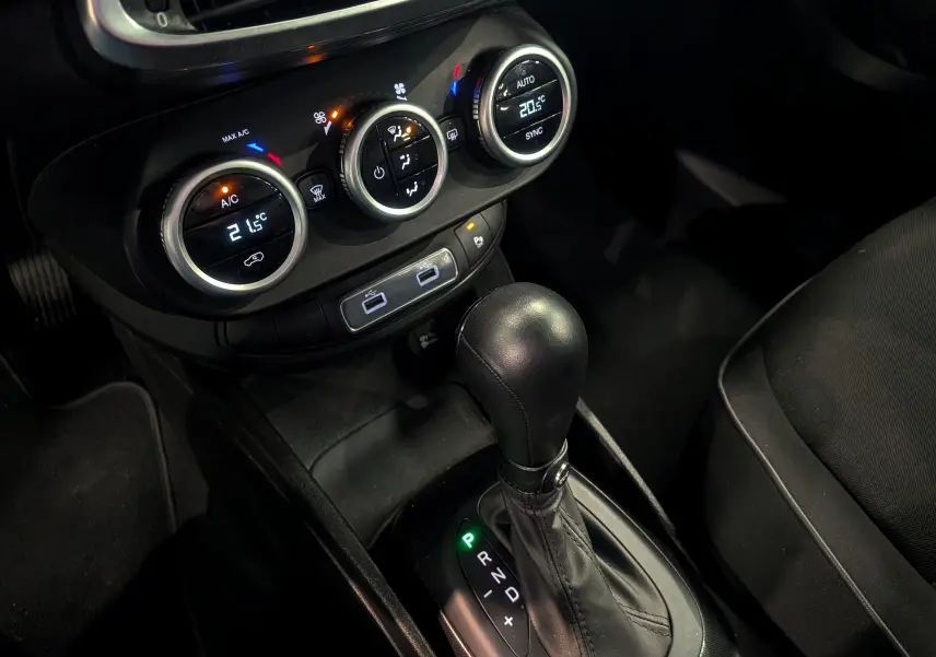 Gros plan sur la console centrale de la Fiat 500X 2024 avec levier de boîte auto et commandes de climatisation digitales.
