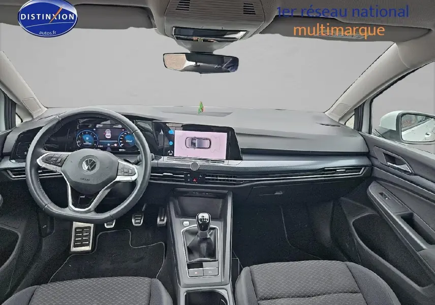 Intérieur avant de la Volkswagen Golf blanche 2021, vue de face sur le tableau de bord et le volant cuir multifonction.