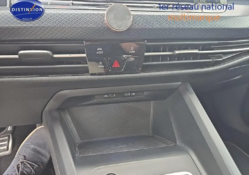 Vue rapprochée de la console centrale noire de la Volkswagen Golf 1.5 TSI essence, avec commandes d’assistance et climatisation.