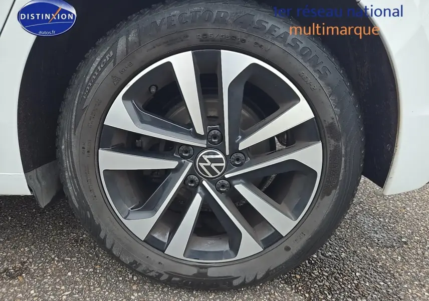 Gros plan sur la roue avant droite d'une Volkswagen Golf blanche avec jante alliage bicolore.