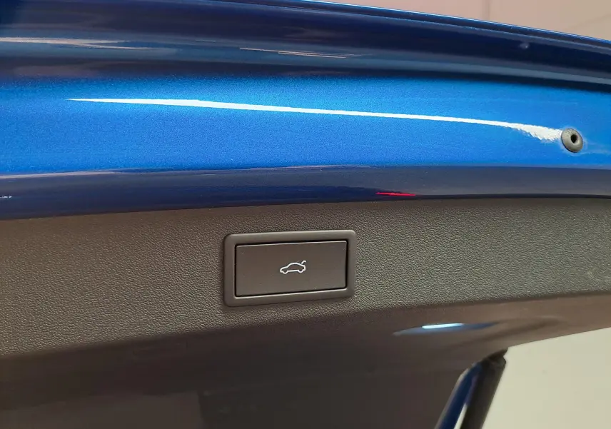 Bouton d'ouverture électrique du coffre sur la partie intérieure du hayon bleu métallisé du Skoda Kodiaq 2025.