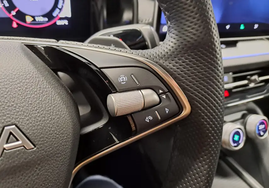 Gros plan sur les commandes au volant perforé du Skoda Kodiaq Sportline 2025, intérieur noir avec détails métalliques.