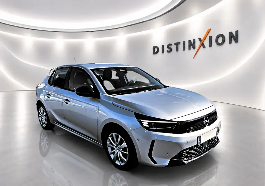 Opel Corsa gris vue 3/4 avant droit dans un showroom lumineux avec logo Distinxion en arrière-plan.