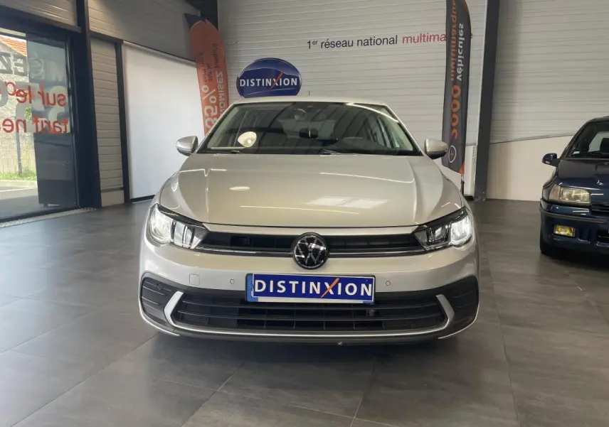 Vue frontale d'une Volkswagen Polo gris clair 2024 avec calandre noire et logo VW bien visible en intérieur showroom.