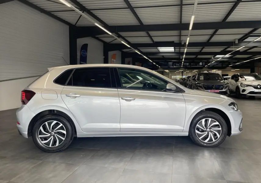 Volkswagen Polo gris clair vue de profil côté gauche, avec jantes alliage et vitres arrière surteintées.