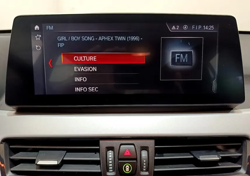 Écran central multimédia affichant la radio FM avec menu de sélection dans l’habitacle d’une BMW X1 sDrive18i Lounge 2019.