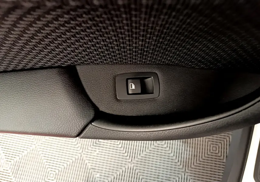 Bouton de verrouillage de porte sur la garniture intérieure noire côté gauche d’un BMW X1 blanc sDrive18i Lounge.