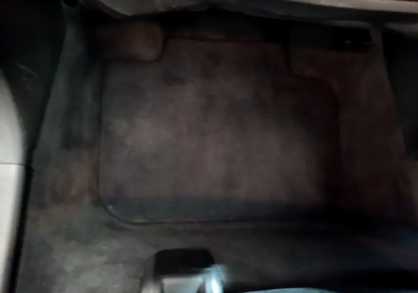 Tapis de sol noir côté conducteur dans l'habitacle d'une BMW X1 sDrive18i Lounge blanche de 2019.