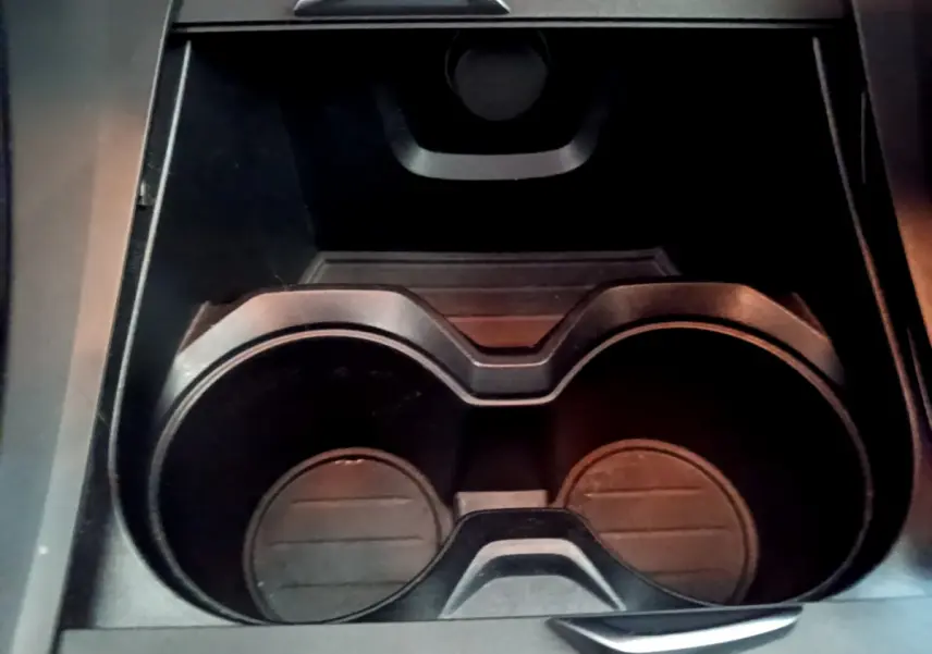 Gros plan sur les porte-gobelets noirs au centre de la console intérieure du BMW X1 sDrive18i Lounge blanc.