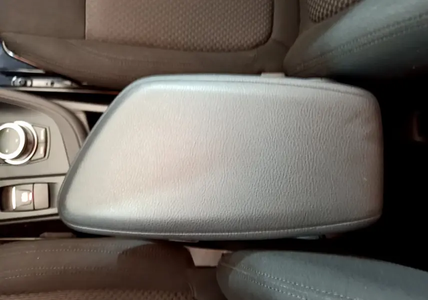 Vue rapprochée de l'accoudoir central en cuir noir et des sièges tissu marron à l'intérieur d'un BMW X1 sDrive18i Lounge.