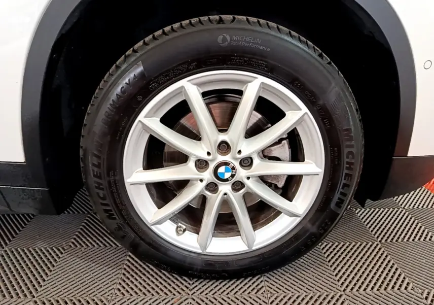 Gros plan sur la roue avant droite blanche d’un BMW X1 sDrive18i Lounge avec jante alliage et pneu Michelin.