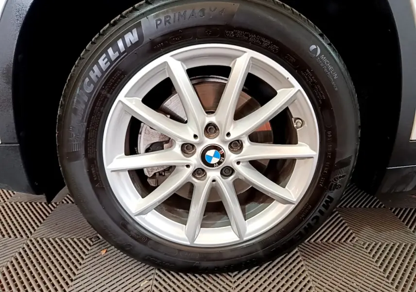 Gros plan sur la roue avant droite d’un BMW X1 blanc, avec jante alliage et pneu Michelin Primacy 4.