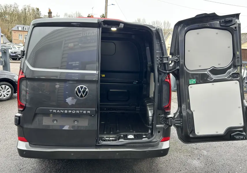 Vue arrière d’un Volkswagen Transporter T7 ProCab graphite Dust avec porte droite ouverte montrant l’espace de chargement vide.
