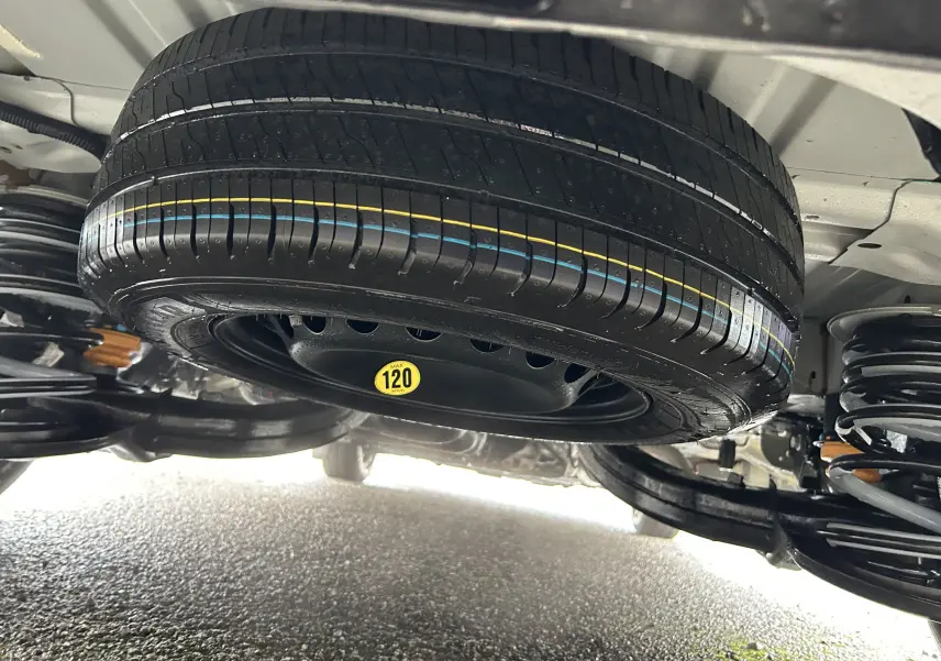 Gros plan sous le Volkswagen Transporter T7 ProCab, roue de secours noire avec marquage jaune 120 km/h visible.