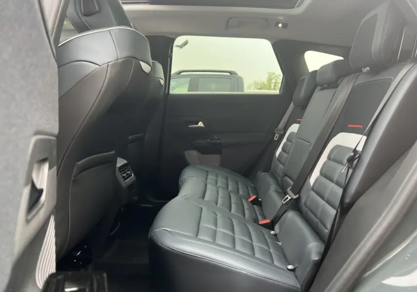 Vue intérieure arrière côté droit du Citroën C5 Aircross 2026, sièges cuir noir matelassés avec toit ouvrant panoramique.