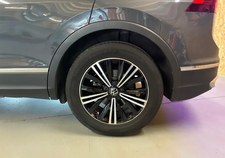Gros plan sur la roue arrière droite du Volkswagen Tiguan gris 2023, avec jante alliage noire et argentée.