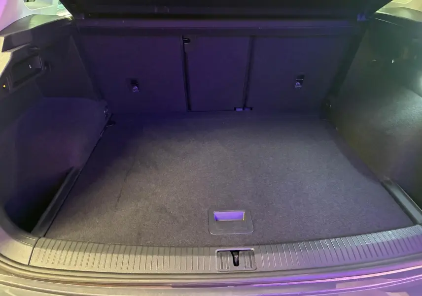 Coffre spacieux du Volkswagen Tiguan 2023 gris, vu de l'arrière avec plancher plat et éclairage intérieur.