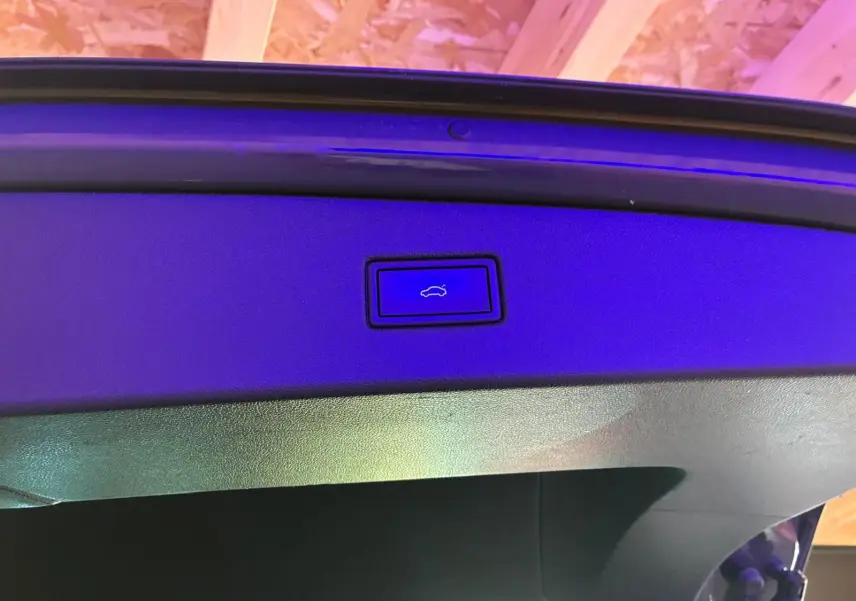 Gros plan sur le bouton d'ouverture électrique du hayon du Volkswagen Tiguan gris, intérieur du coffre visible.