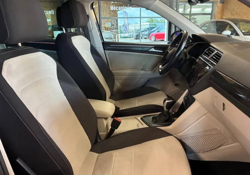 Vue intérieure côté droit du Volkswagen Tiguan 2023, sièges bicolores beige et noir avec tableau de bord moderne.