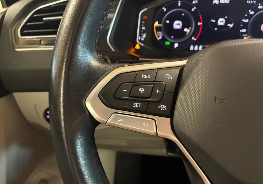 Gros plan sur le volant multifonctions noir du Volkswagen Tiguan 2023 avec commandes de régulateur de vitesse et tableau de bord digital.