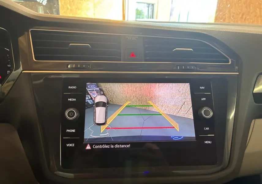 Vue intérieure du tableau de bord du Volkswagen Tiguan 2023, écran tactile affichant la caméra de recul avec guidage coloré.
