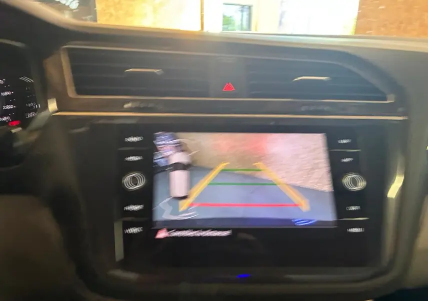 Écran tactile central du Volkswagen Tiguan 2023 montrant la caméra de recul avec lignes de guidage en intérieur noir.