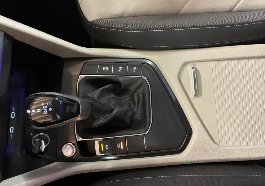 Vue rapprochée de la console centrale beige et noire du Volkswagen Tiguan 2023 avec levier de boîte auto et bouton start/stop.
