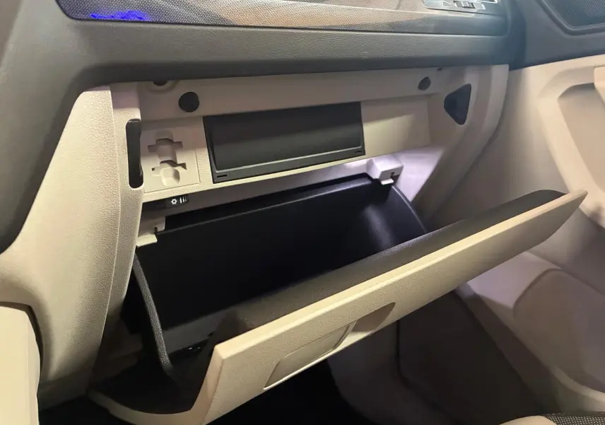 Vue intérieure côté passager du Volkswagen Tiguan 2023, boîte à gants beige ouverte avec tableau de bord noir.