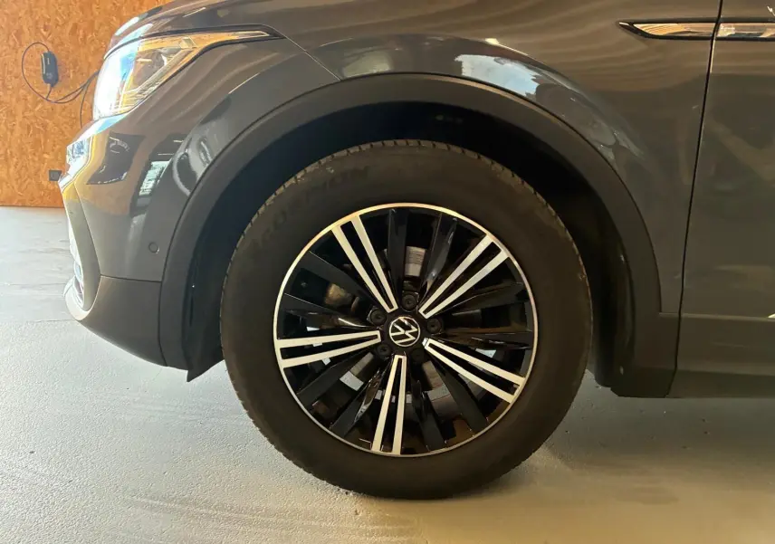 Gros plan sur la roue avant gauche du Volkswagen Tiguan gris 2023 avec jante alliage noire et argentée.
